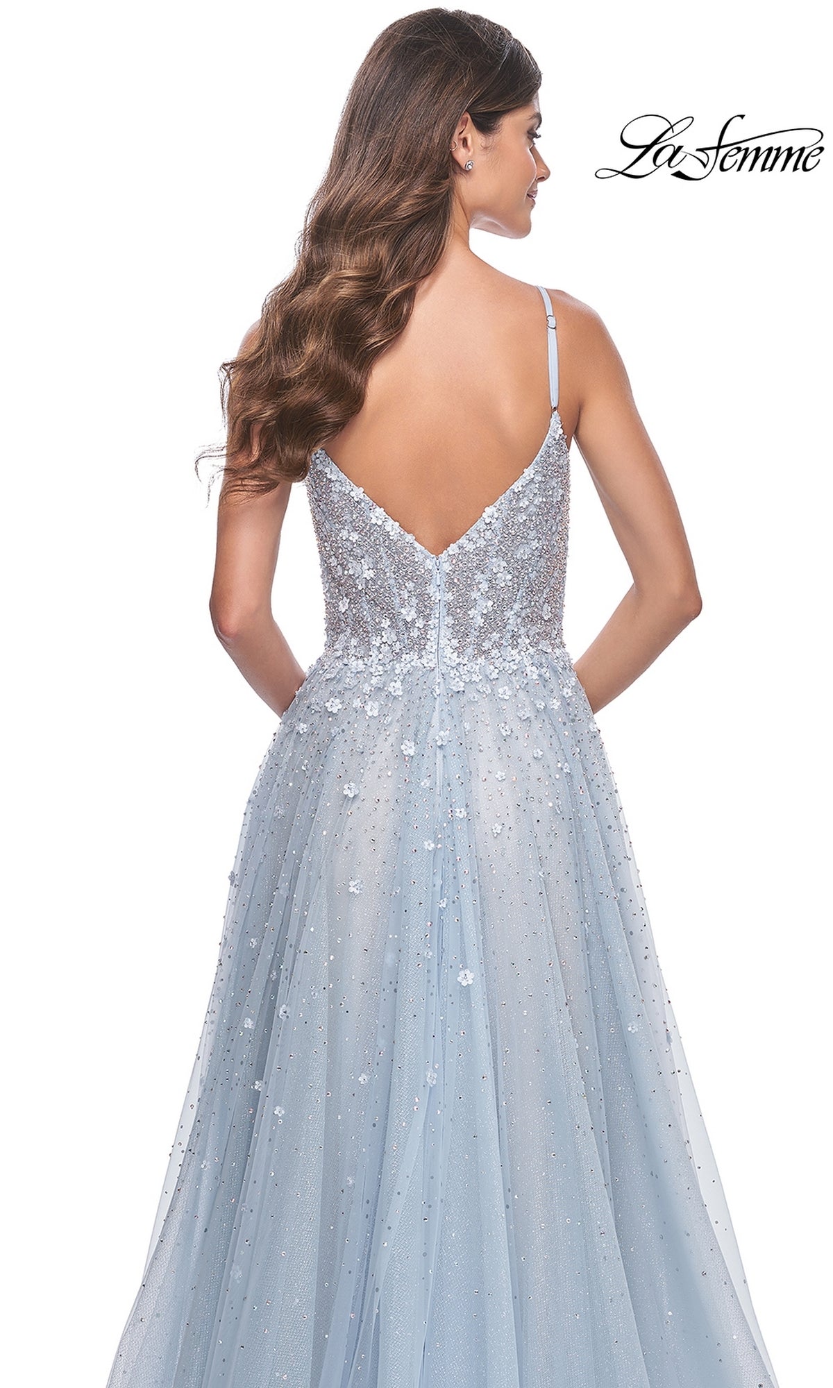 A woman with long wavy hair is shown from the back wearing the La Femme Embellished Long A-Line Prom Dress 32215, a light blue sleeveless gown with sequin and floral details, thin straps, and a V-shaped back.